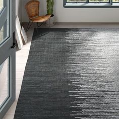 a black and white area rug in an empty room with a chair next to it