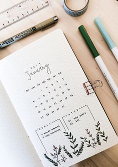 an open planner sitting on top of a wooden table next to a pen and ruler