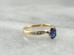 This is a graceful piece, easy to wear and very sweet. The tapered shoulders of this ring are feminine, graced with a little glitter, in the tapering diamond channels. White gold prongs frame the stone to perfection, presenting it in all of its true blue glory! Metal: 14K Yellow and White Gold Gem: Sapphire .64 Carat Gem Measurements: 4.1 x 5.5 mm, Oval Accents: 8 Diamonds totaling .08 Carat Ring Size: 5 Marks: "SMG14K" Stamped on the inside band Ring For Engagement, Sapphire Solitaire Ring, Sapphire And Diamond Ring, Three Stone Diamond, Purple Sapphire, French Blue, Gold Pattern, Rings Wedding, True Blue