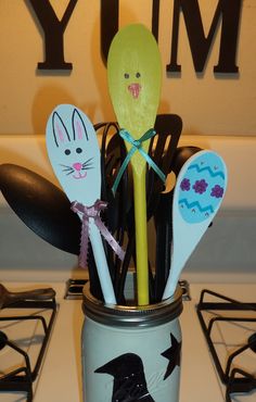 some spoons are sticking out of a jar on the stove top with other kitchen utensils in it