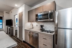 a kitchen with stainless steel appliances and white counter tops, along with hardwood flooring