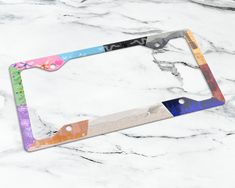 a multicolored license plate frame sitting on a marble surface