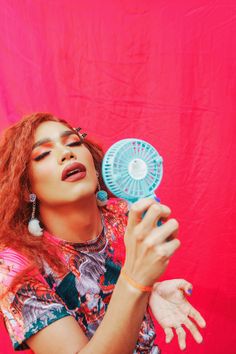 a woman with red hair is holding a fan in her hand and looking up at the sky