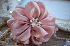 a close up of a flower on a table with pearls and other items in the background