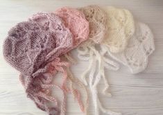 five different colors of crochet lace on a white wooden surface, one is pink and the other is beige