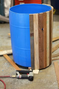 a large blue barrel sitting on top of a floor next to some wood planks