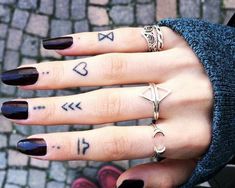 a woman's hand with tattoos on her fingers and two different rings in the middle