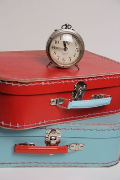 an alarm clock is sitting on top of two suitcases that are both red and blue