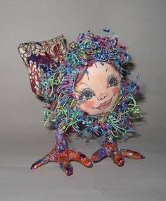 an odd looking doll made out of wire and plastic beads with hair on it's head