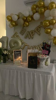 a table topped with balloons and other items next to a sign that reads happy birthday