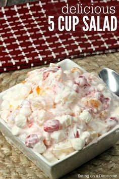 a small bowl filled with fruit salad next to a red and white table cloth on top of