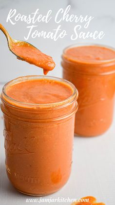 two jars of roasted cherry tomato sauce with a spoon in one jar and an orange slice on the other