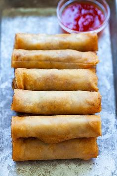 four deep fried spring rolls on a baking sheet with ketchup