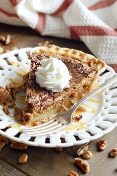 a slice of pecan pie on a white plate with a fork and whipped cream