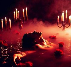 a woman laying in a hot tub surrounded by candles