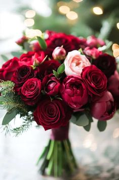 a bouquet of red and pink flowers sitting on top of a table next to a christmas tree