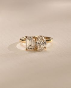 three stone engagement ring with diamond accents in yellow gold and white diamonds, on a plain surface