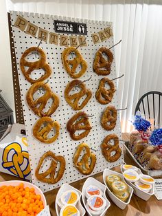 an assortment of pretzels are displayed on a table with other snacks and desserts