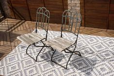 two metal chairs sitting on top of a white and gray rug next to a brick wall