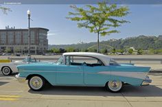 an old blue and white car parked in a parking lot