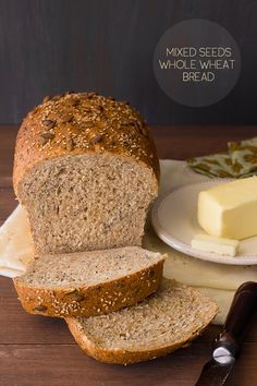 a loaf of bread sitting on top of a wooden table next to butter and a knife