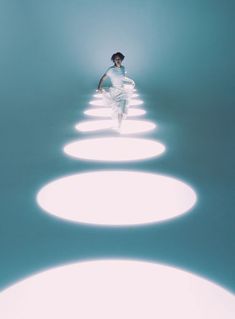 a man in white is walking through the middle of an empty room with circles on it