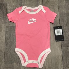 Pink & White Baby Girl Bike Onesie Casual Pink Onesie With Letter Print, Casual White Onesie For First Birthday, Casual Pink Onesie For Playtime, Nike Casual Onesie For Playtime, Casual Nike Onesie For Playtime, Casual White Onesie For Sports, White Casual Onesie For Sports, Nike Baby Clothes, Nike Romper