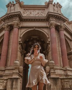 a woman standing in front of an ornate building with her hands clasped to her face