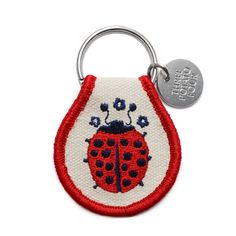 a red and white keychain with a ladybug on it's side