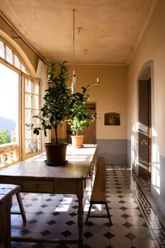 a room with a table, bench and potted plant on the window sill