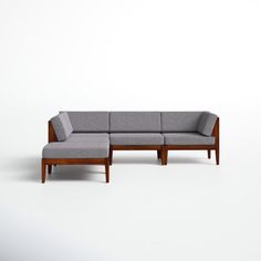 a gray couch sitting on top of a white floor next to a wooden frame chair