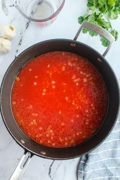 a pot filled with red sauce next to garlic and parsley