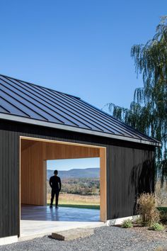 a man standing in the doorway of a small building with a metal roof on top