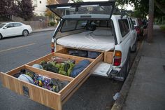 an open trunk in the back of a white truck with its bed pulled out on the street