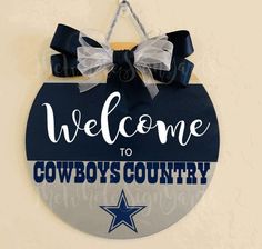 a sign that says welcome to cowboys country hanging from a wall with bows on it