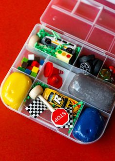 a plastic container filled with legos and other assorted toy items on a red surface