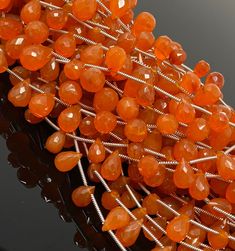 an orange beaded bracelet with lots of beads and silver wire on top of black surface