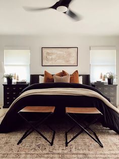 a bedroom with a bed, two chairs and a ceiling fan