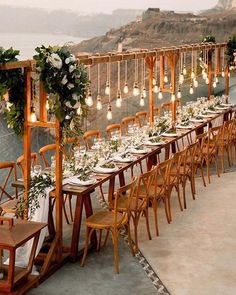 a long table is set up with white flowers and greenery for an outdoor wedding reception