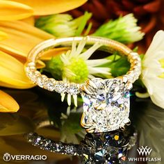 a diamond ring sitting on top of a table next to yellow flowers and white daisies