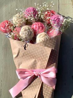 a brown paper bag with pink and white flowers in it on a wooden table next to a wall