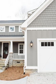 a gray house with white trim and two garage doors