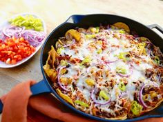 a skillet filled with taco salad and tortilla chips on top of a wooden table