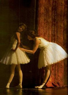 two young ballerinas in white tutu skirts are touching each other's hands