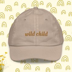 a baseball cap with the words wild child embroidered on it, next to yellow flowers