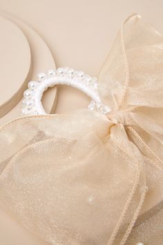 You don't need a reason to add a too-cute addition like the Lulus Darling Purpose Beige Organza Pearl Bow Ponytail Holder to your look! This adorable accessory starts with an elastic, white hair tie adorned with gleaming faux pearls, supporting a classic organza hair bow (with a subtle sheen and matching faux pearls throughout) that completes the balletcore-inspired design! Bow Measures 7. 5" Wide. Ribbon Measures 6" Long. 80% Polyester, 20% Acrylic. Imported. Lulus | Darling Purpose Beige Organza Pearl Bow Ponytail Holder. Bow Hair Tie, Bow Ponytail, Pearl Bow, Ponytail Holder, Bow Hair, Ponytail Holders, Hair Tie, White Hair, Hair Bow