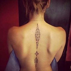 the back of a woman's neck with an intricate tattoo on her left side