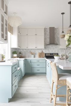 a kitchen with light blue cabinets and white counter tops, an island in the middle