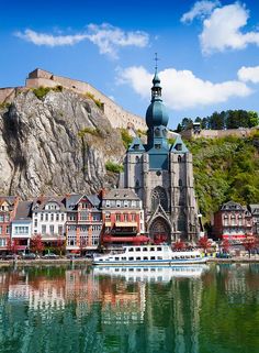 a boat is in the water near some buildings and a castle on top of a hill