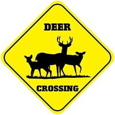 a yellow deer crossing sign sitting on the side of a road next to another animal